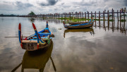 Two boats sit on the lake near Mandalay as Om Pei bridge stretches out to the other side.